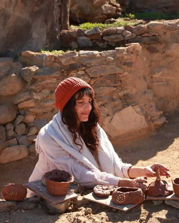 Woman shaping clay pots outdoors