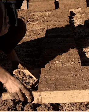 Hands shaping mud bricks