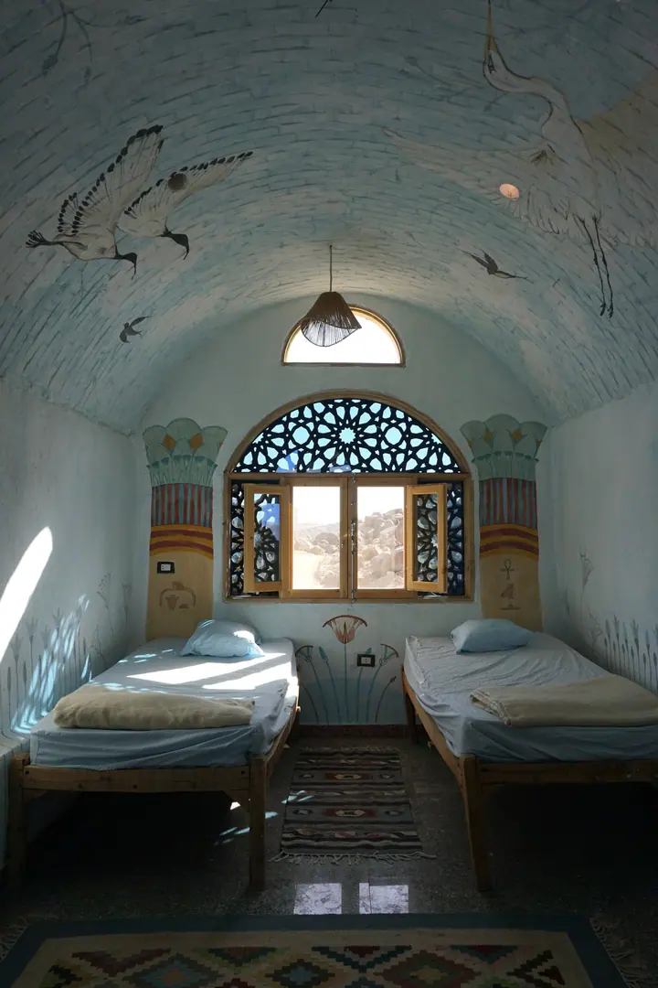 Twin beds beneath a vaulted ceiling painted with birds